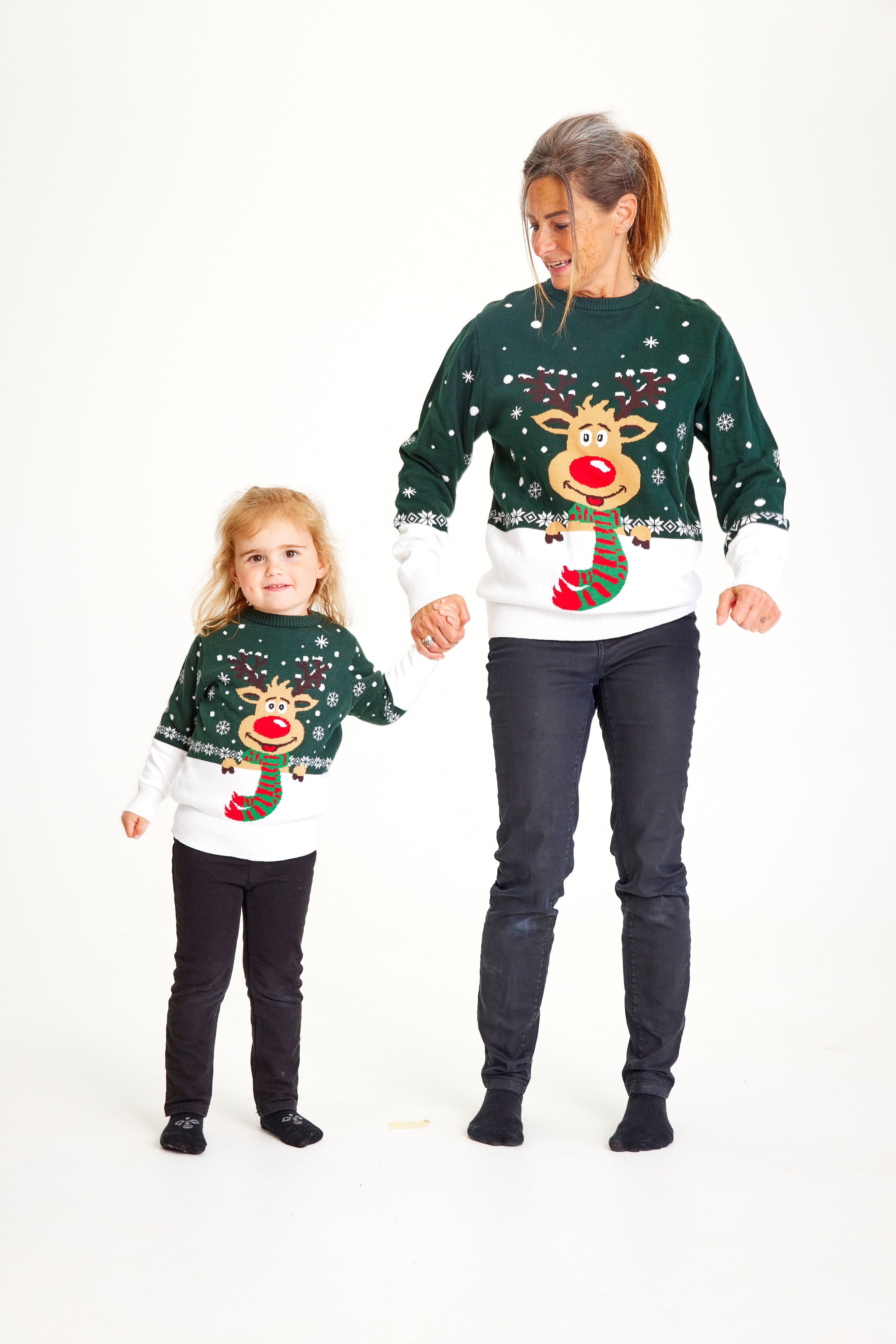 Un enfant et une femme portant un pull de Noël vert et blanc avec Rudolph.